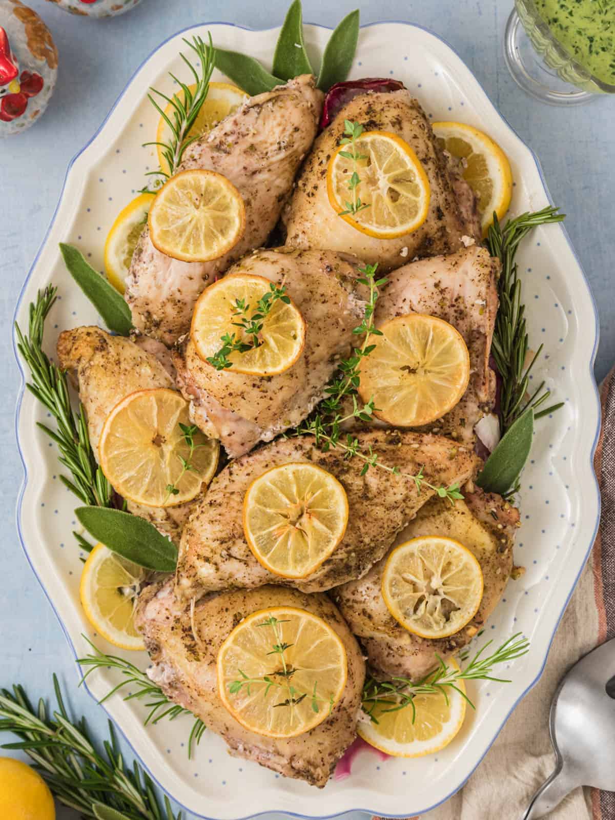 A platter of za'atar roasted with chicken with lemon slices and fresh herbs.
