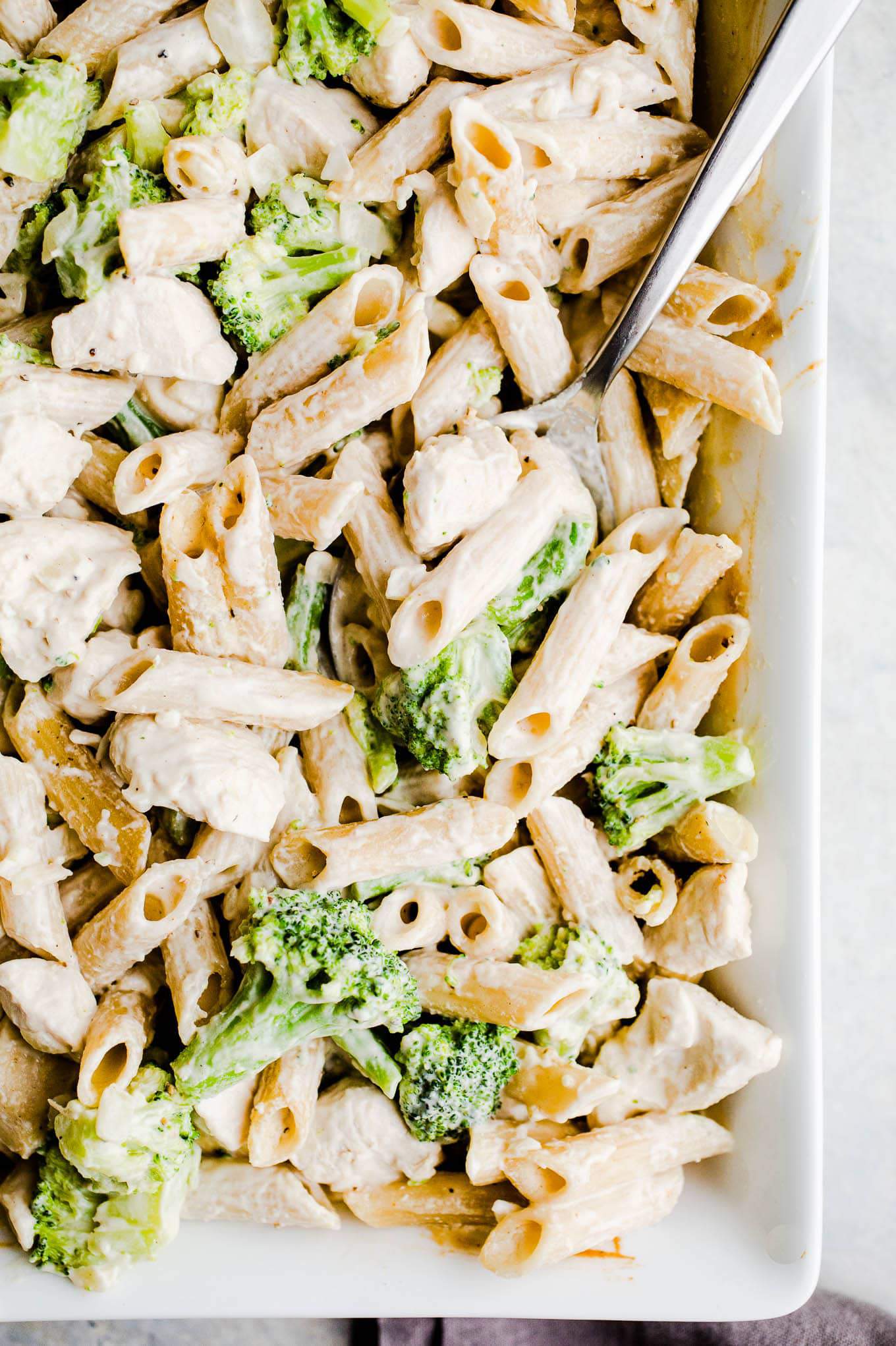 Chicken and broccoli with alfredo sauce and pasta in a serving dish.