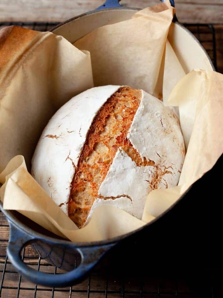 A loaf of gluten free artisan bread sitting inside a dutch oven pot.