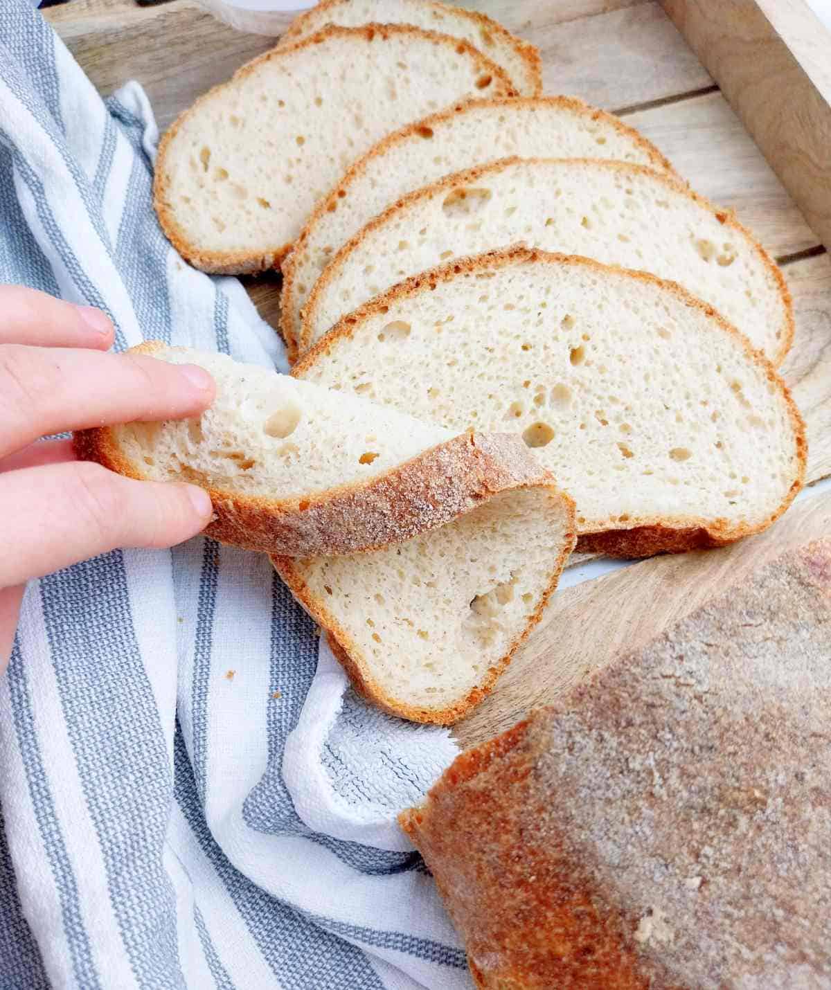 A hand picking up a slice of gluten free sourdough bread.