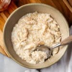A spoon scooping a bite of chicken and rice from a serving bowl.