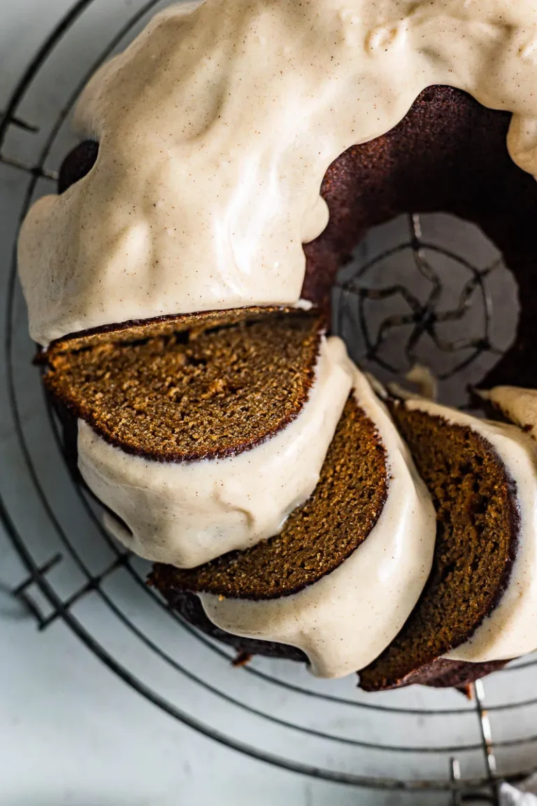 A gluten free gingerbread bundt cake cut into slices and sitting on a round wire rack.