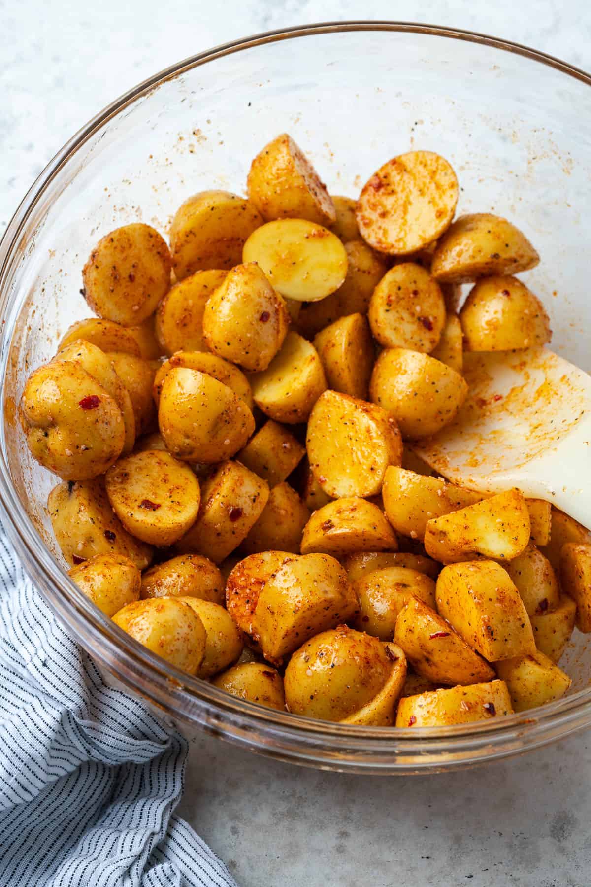 Cut baby potatoes covered with oil and spices in a large mixing bowl. 