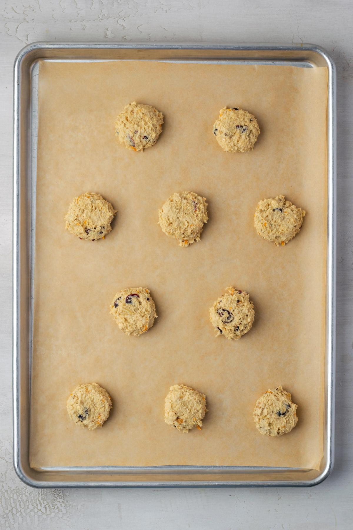Cookie dough balls laid out on a parchment paper lined baking sheet. 