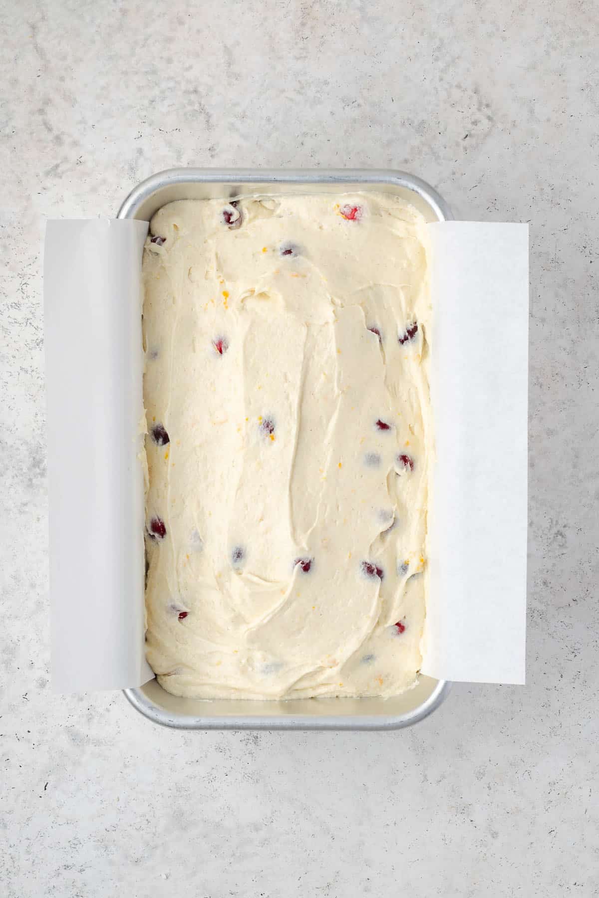 Cranberry orange pound cake batter spread into a loaf pan. 