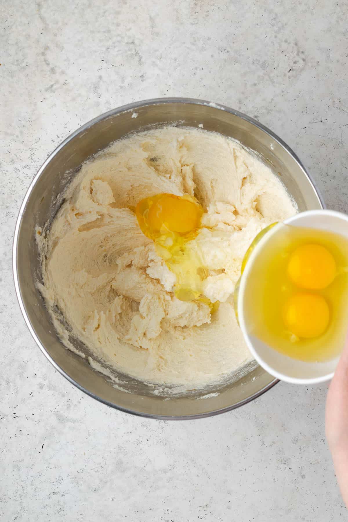 Eggs being added one at a time to the partially mixed cake batter.