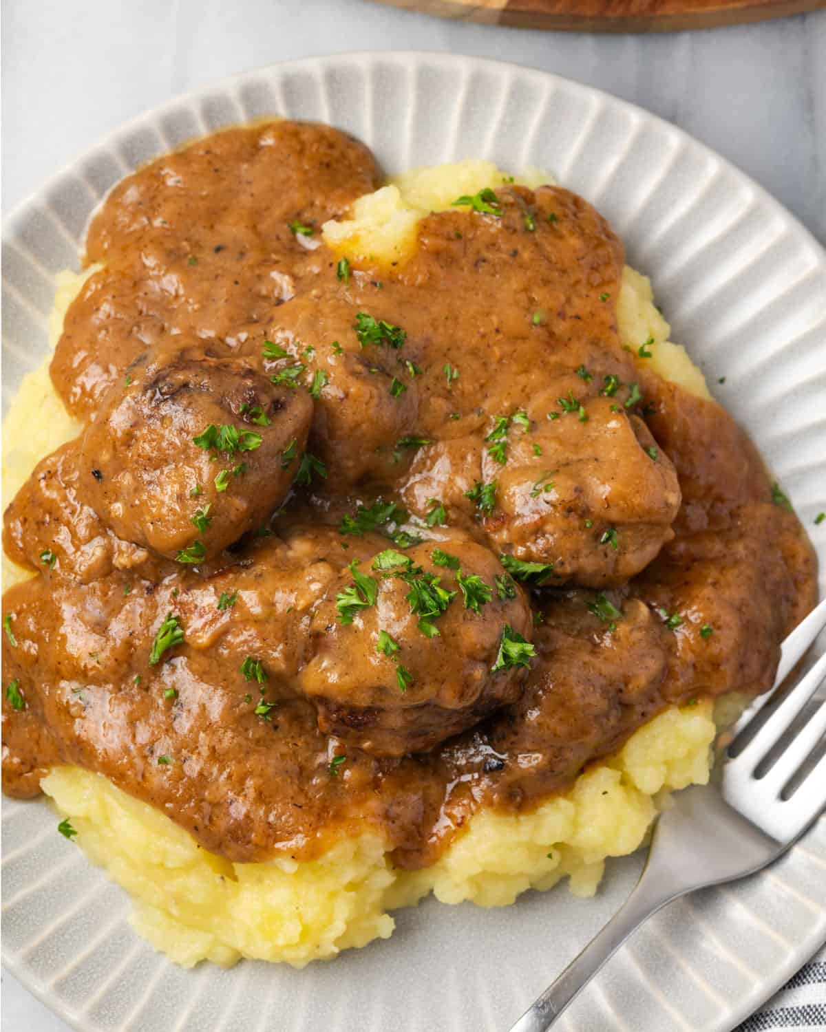 Swedish meatballs in brown gravy served over a pile of mashed potatoes.