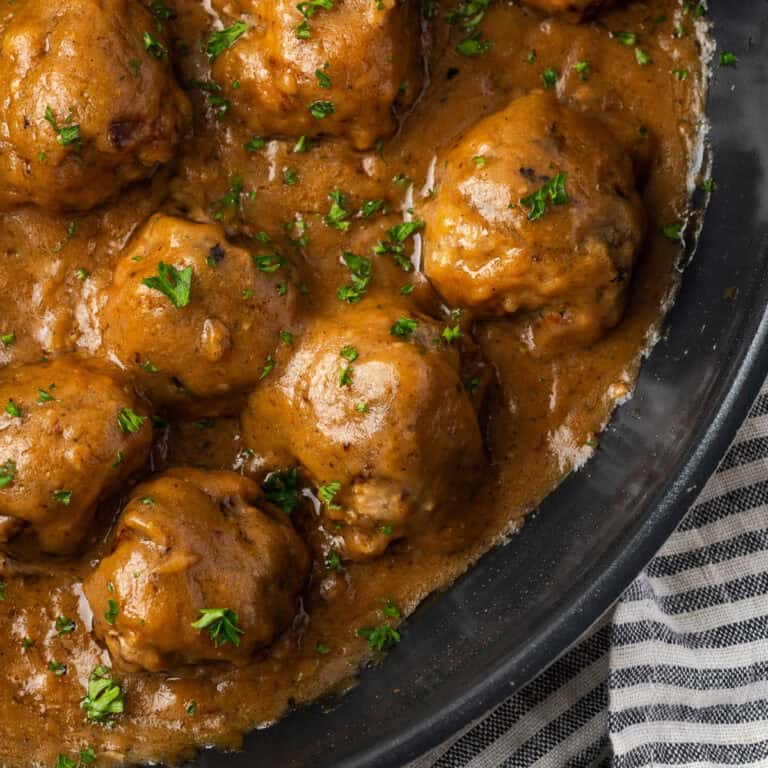 Swedish meatballs in brown gravy served from a large pan.