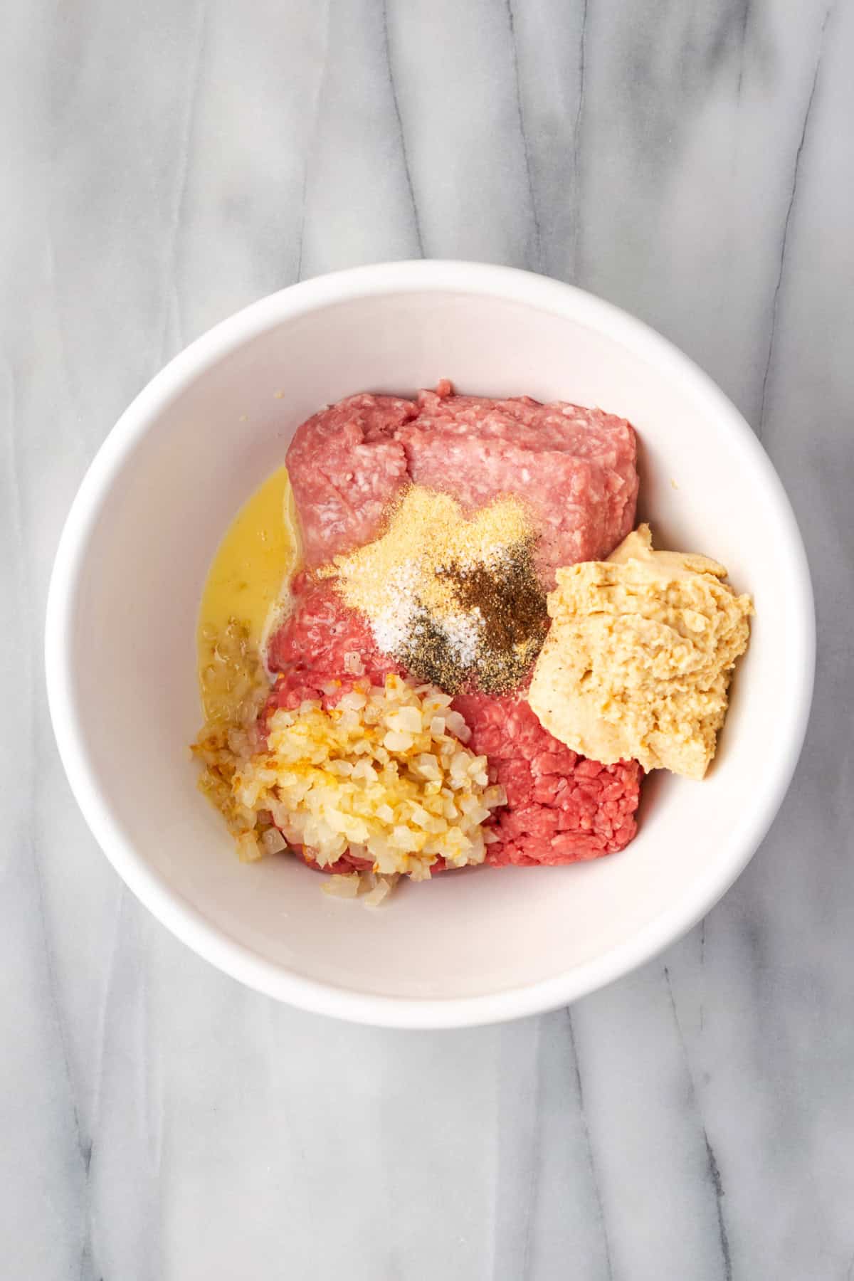 Ground beef, ground pork, egg, cooked onion, soaked bread crumbs and spices combined together in a large mixing bowl. 