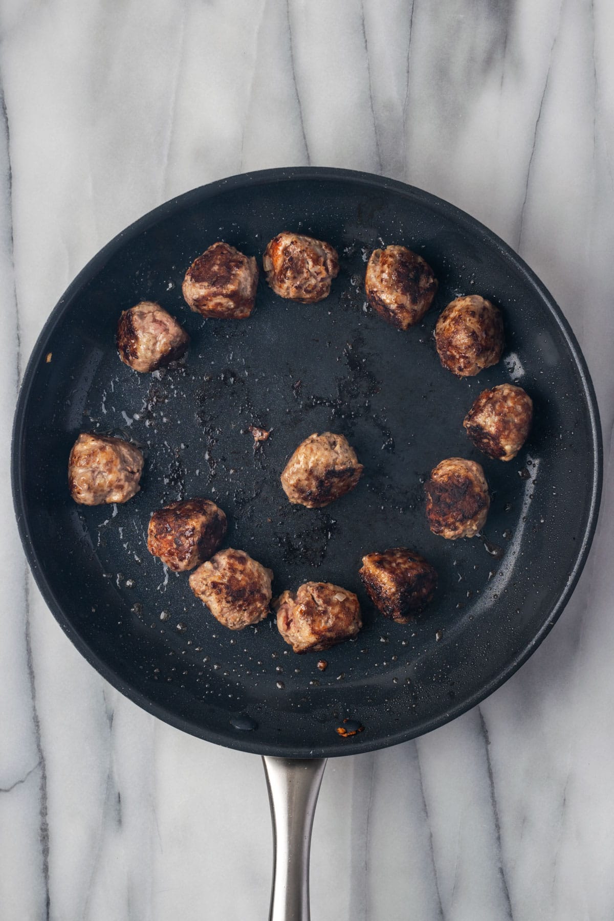 Cooked meatballs in a large skillet.