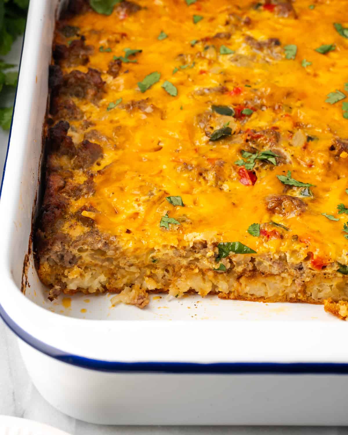 A sliced breakfast casserole showing the tater tot layer, eggs and sausage inside.