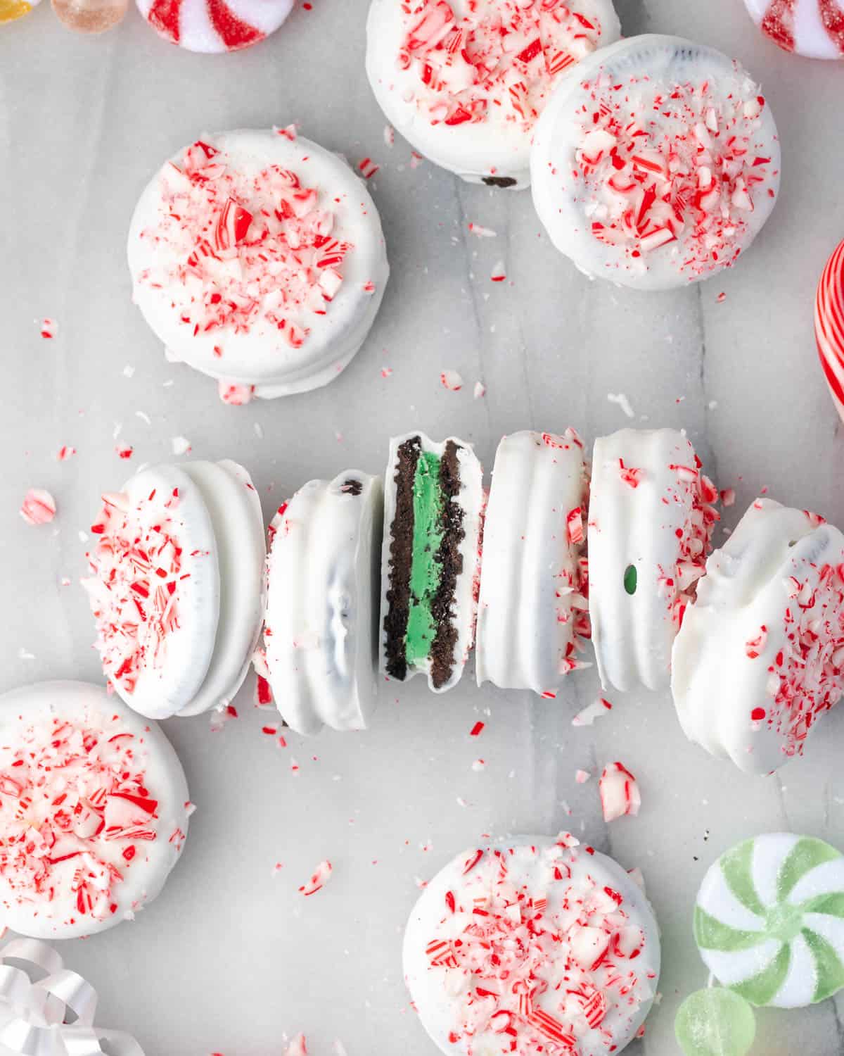 Candy cane and white chocolate Oreo cookies scattered on a marble counter.