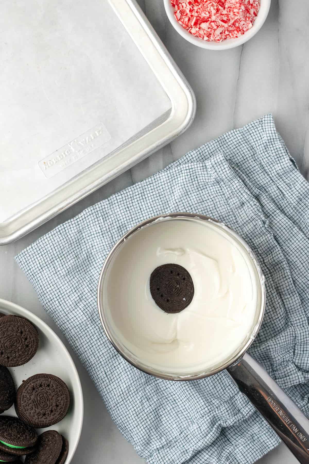 A single Oreo cookie being dipped in melted white chocolate.