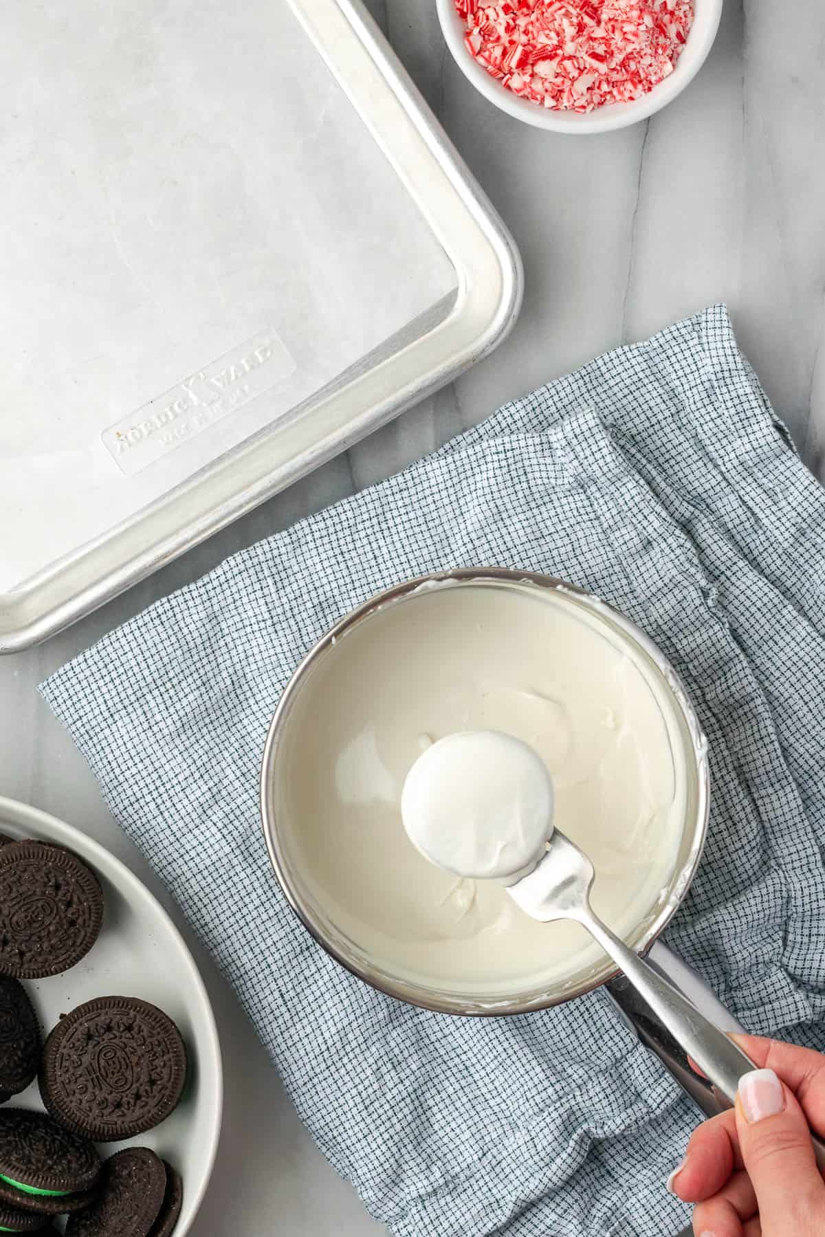 A white chocolate covered Oreo cookie being lifted out of the pan with a fork. 