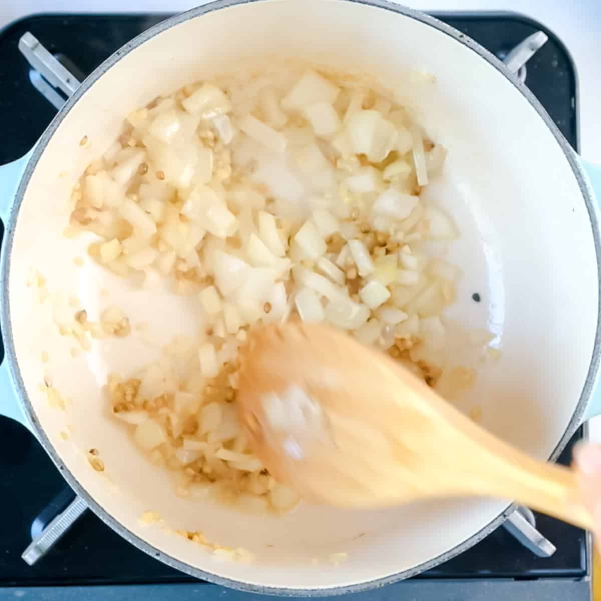 Onions being sauteed in a dutch oven pot.