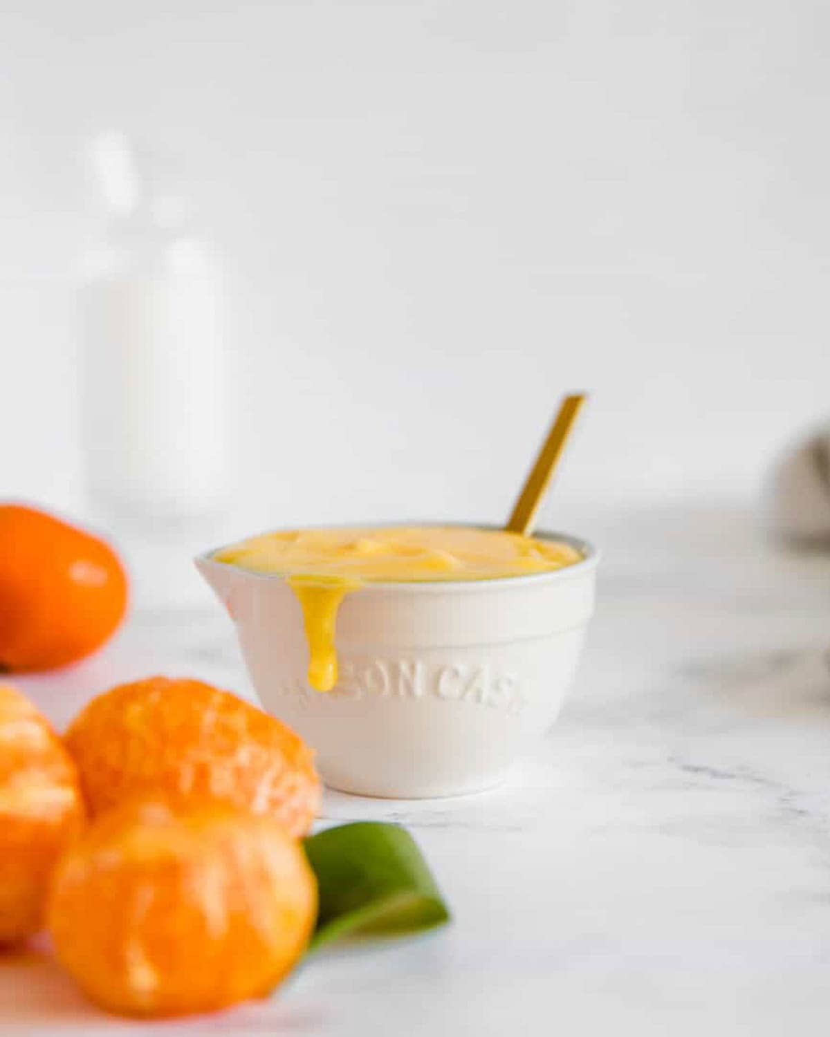 A bowl of clementine curd sitting on a marble counter.