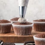 Cookie and cream frosting being piped onto a chocolate cupcake.