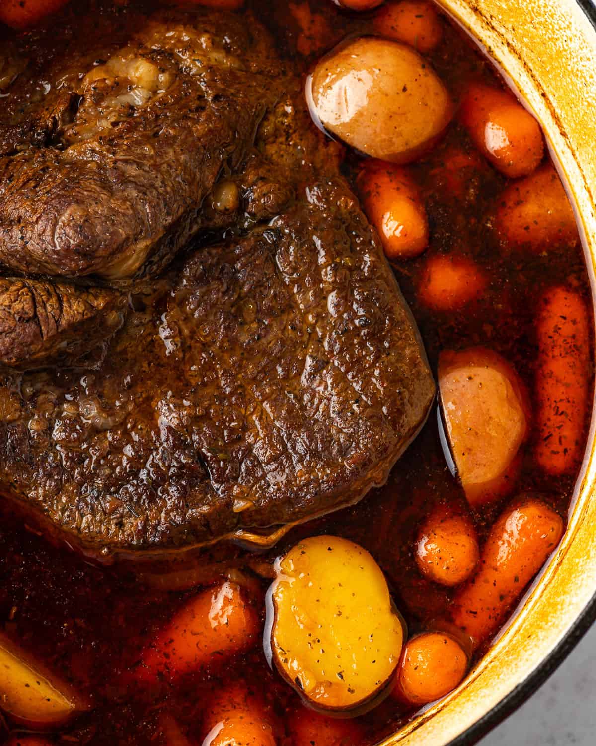A pot roast with new potatoes and carrots in a Dutch oven.
