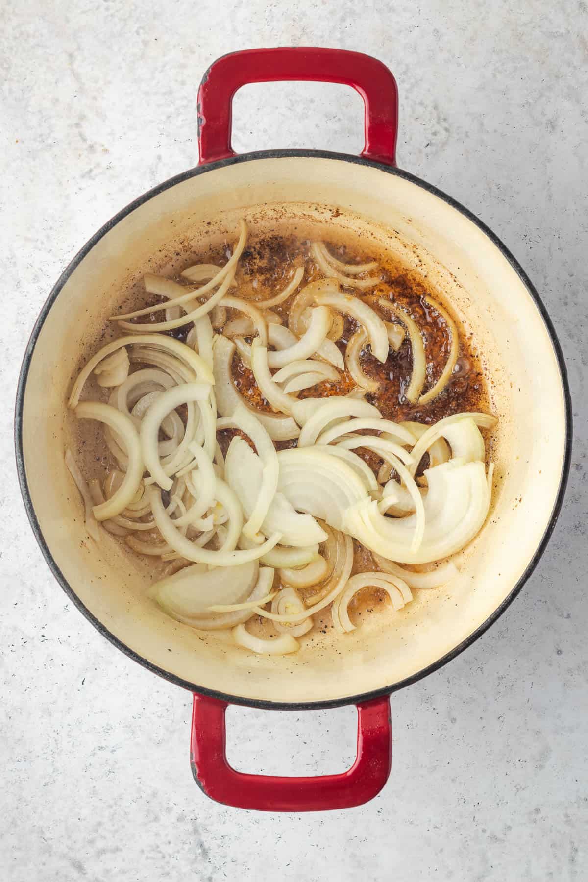 Sliced onions added into the Dutch oven pot with the remaining oil.