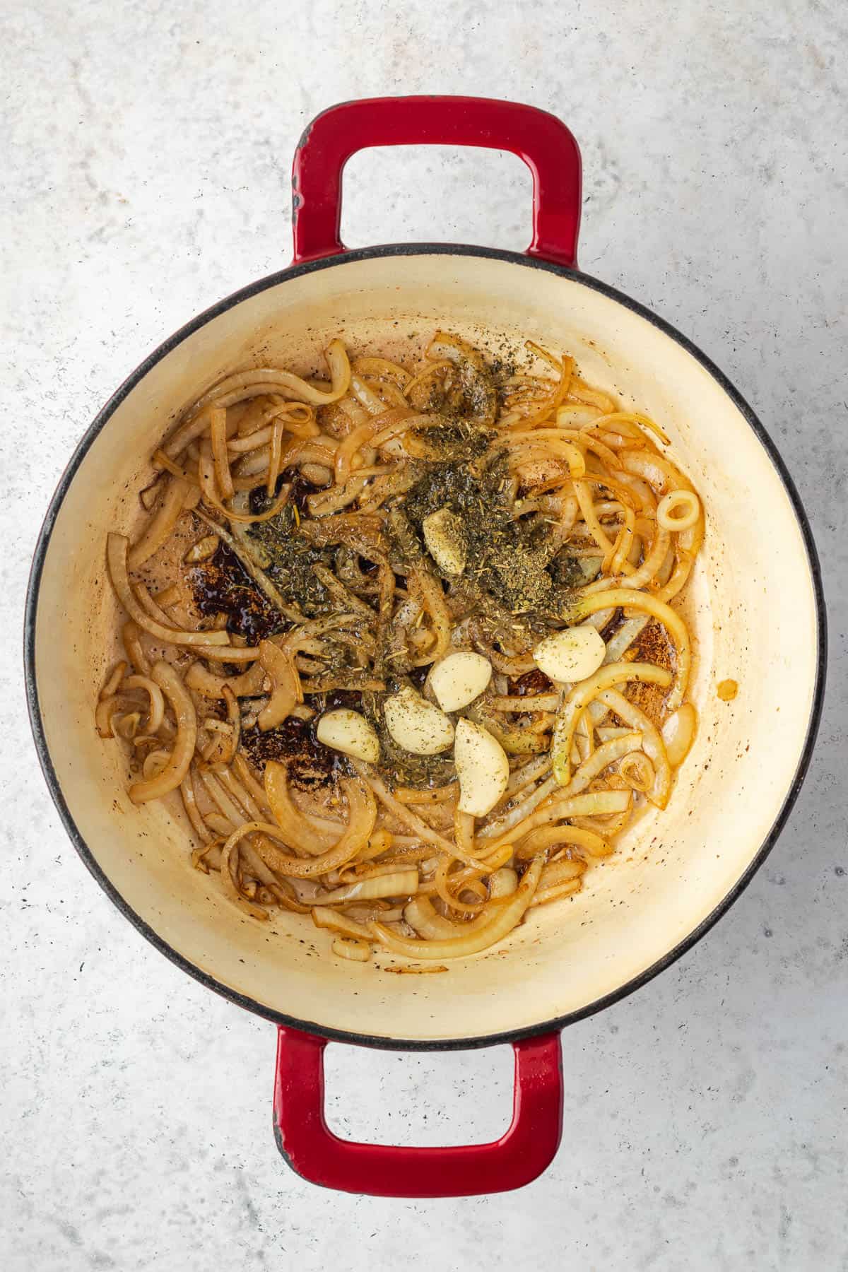 Garlic and dried herbs being added to the cooked onions.