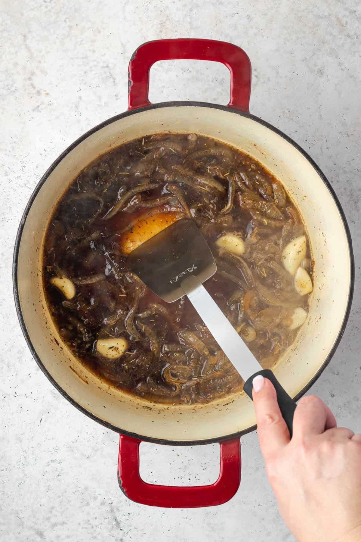 A spatula being used to deglaze the bottom of the pot.