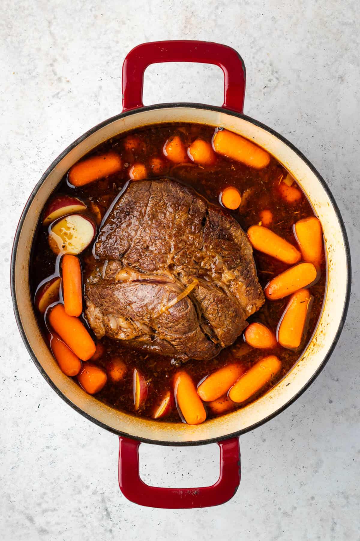 Pot roast with carrots and potatoes in a large Dutch oven pot.