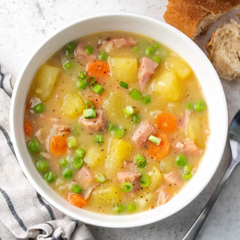 A bowl of creamy ham and potato soup garnished with green onions.