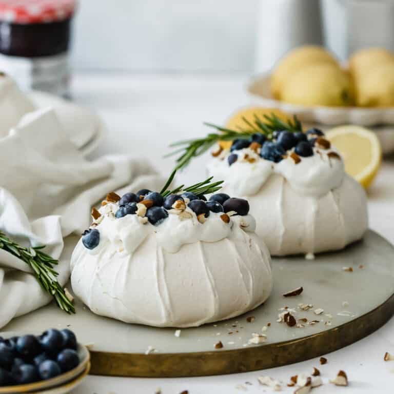 Two mini pavlova nests sitting on a marble serving tray.