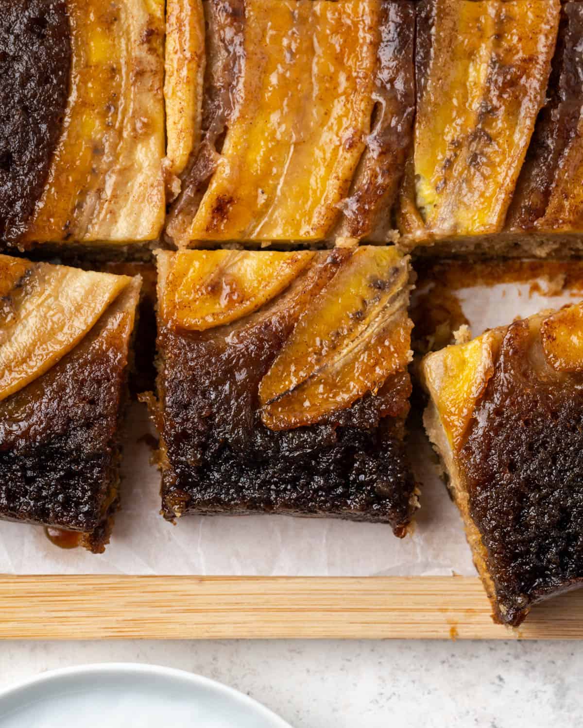 A bananas foster upside down cake sliced into squares sitting on a cutting board.