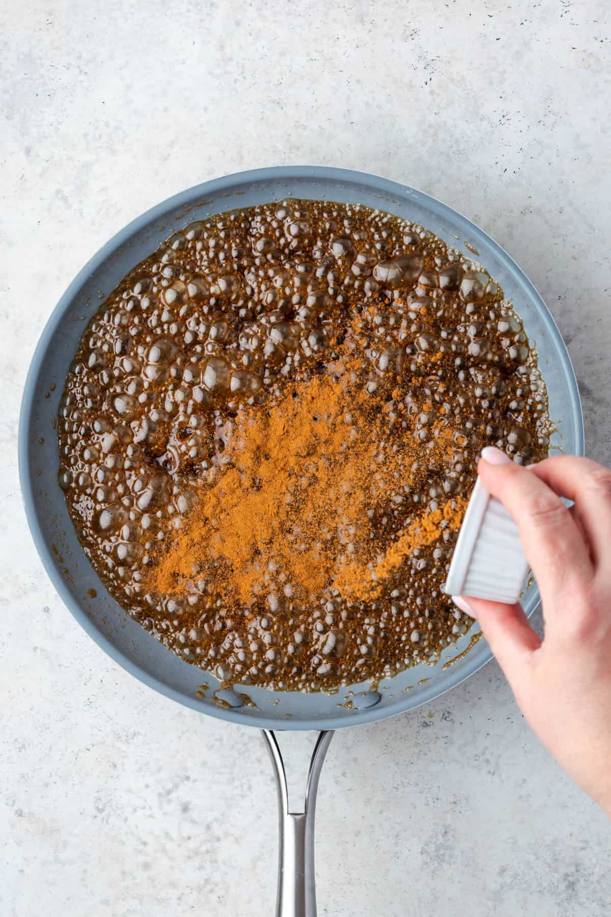 Cinnamon being added into the cooked caramel sauce.