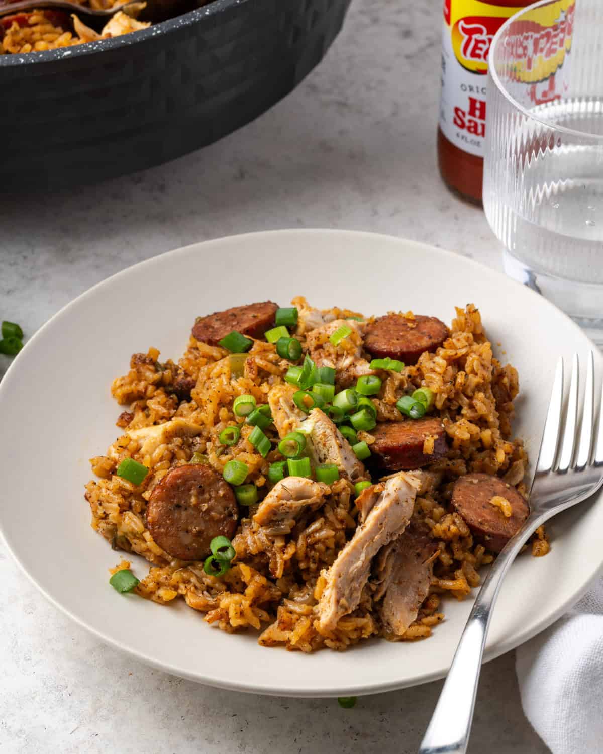 A serving plate with chicken and sausage jambalaya topped with green onions.