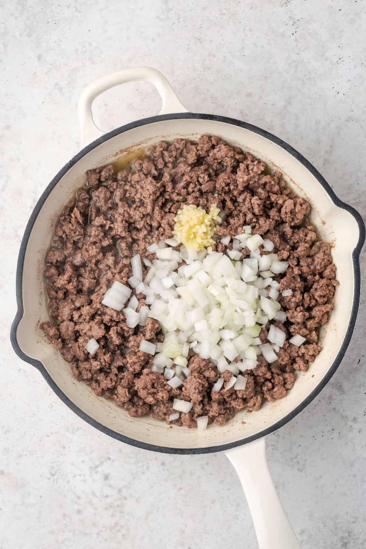 Onion and garlic added to the pan with the cooked ground beef.