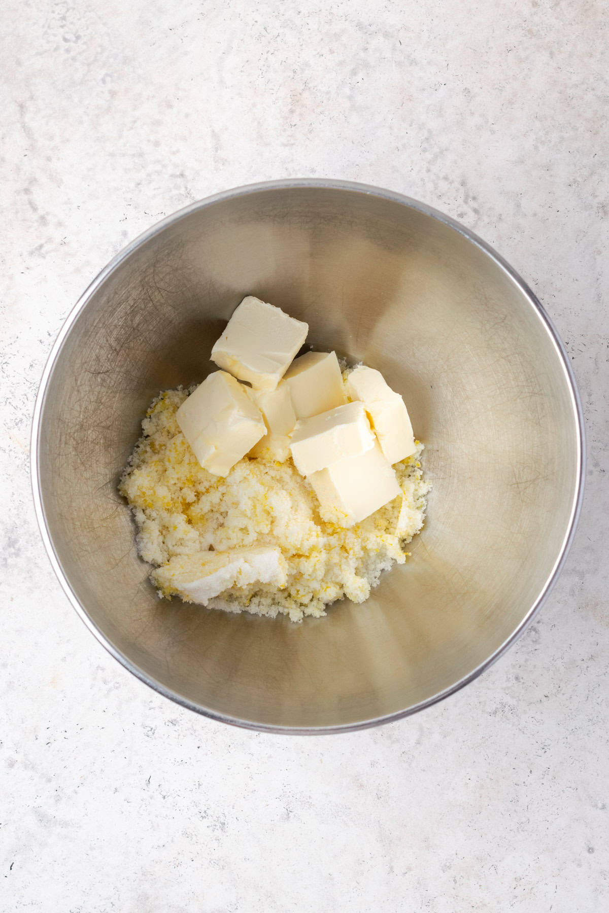 Butter and lemon zest sugar combined in a large metal mixing bowl. 