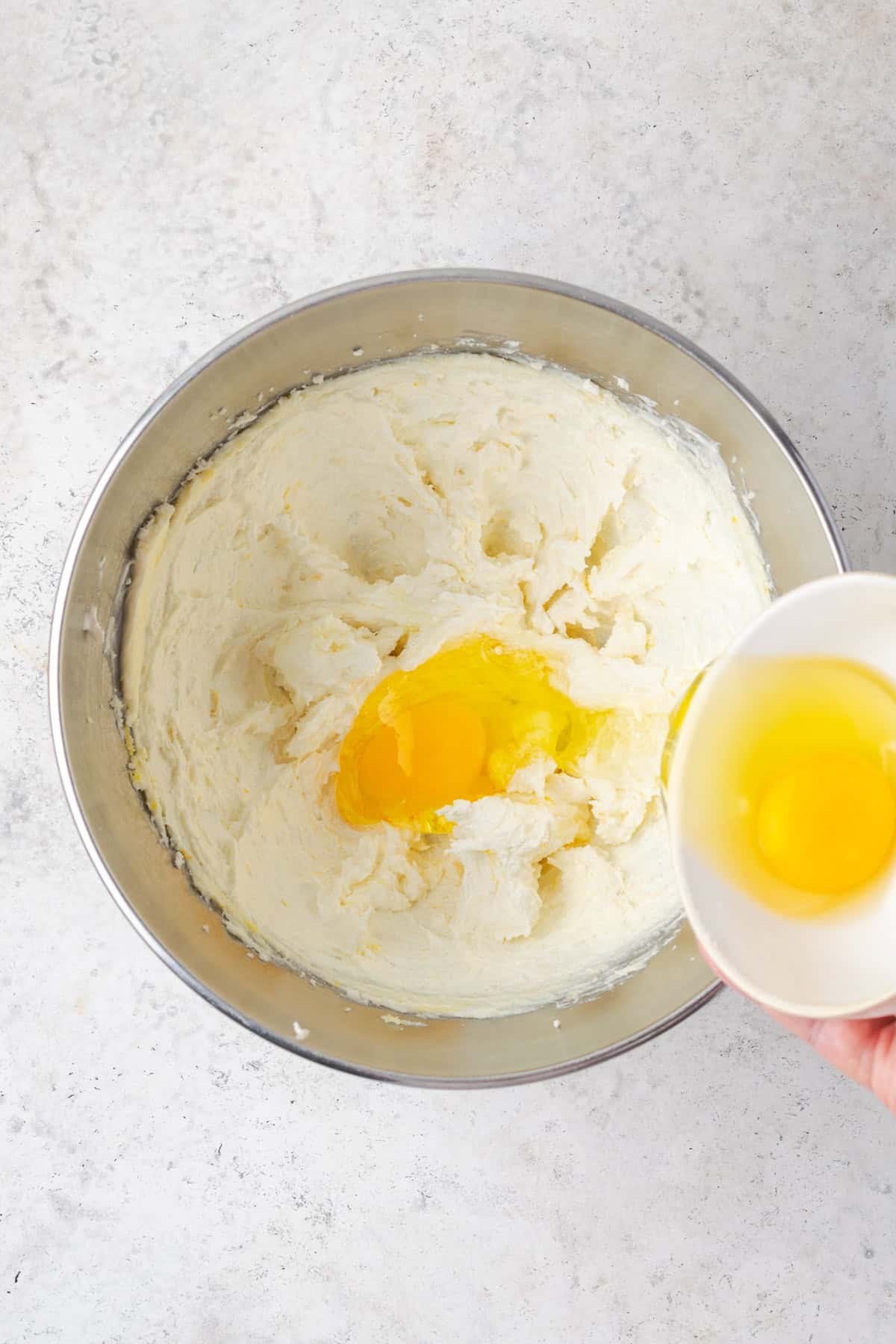 Eggs being added to the bowl with the creamed butter and sugar.