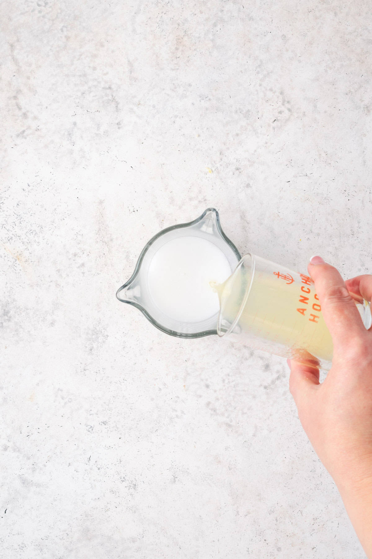 Lemon juice being poured into a cup of milk. 