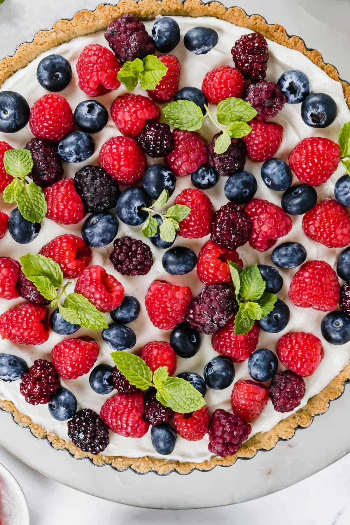 A creamy tart covered with fresh berries.