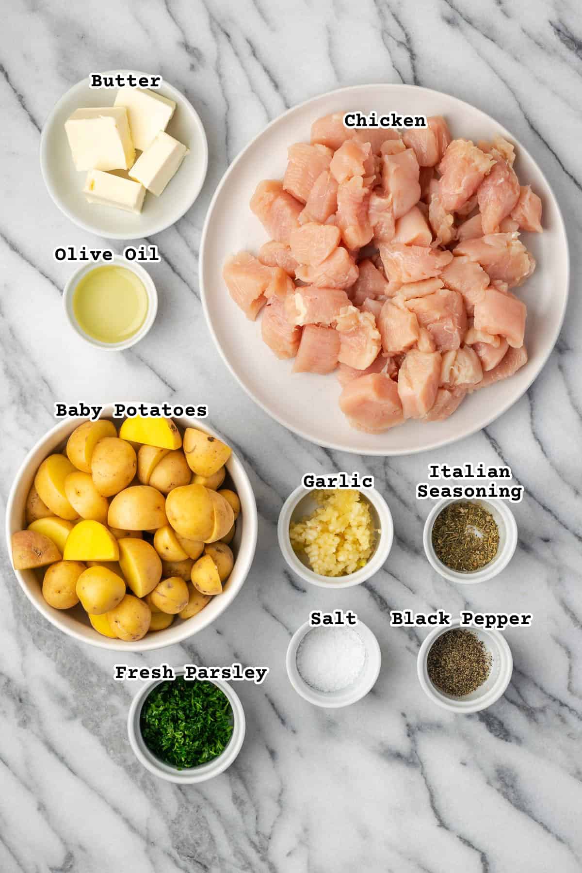 Ingredients for garlic butter chicken and potatoes sitting on a marble counter.