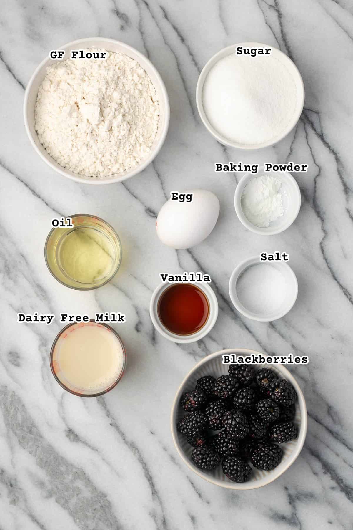 Ingredients for gluten free blackberry muffins sitting on a marble countertop.
