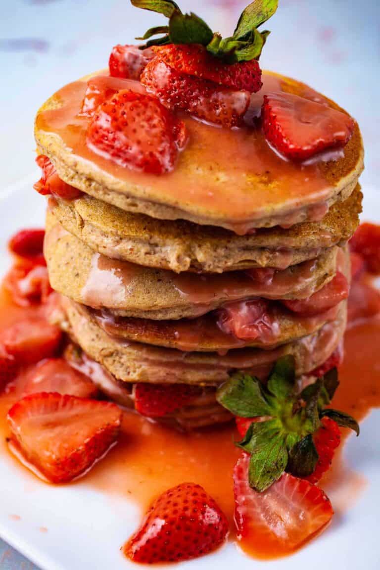 A tall stack of plantain pancakes topped with fresh strawberry syrup. 