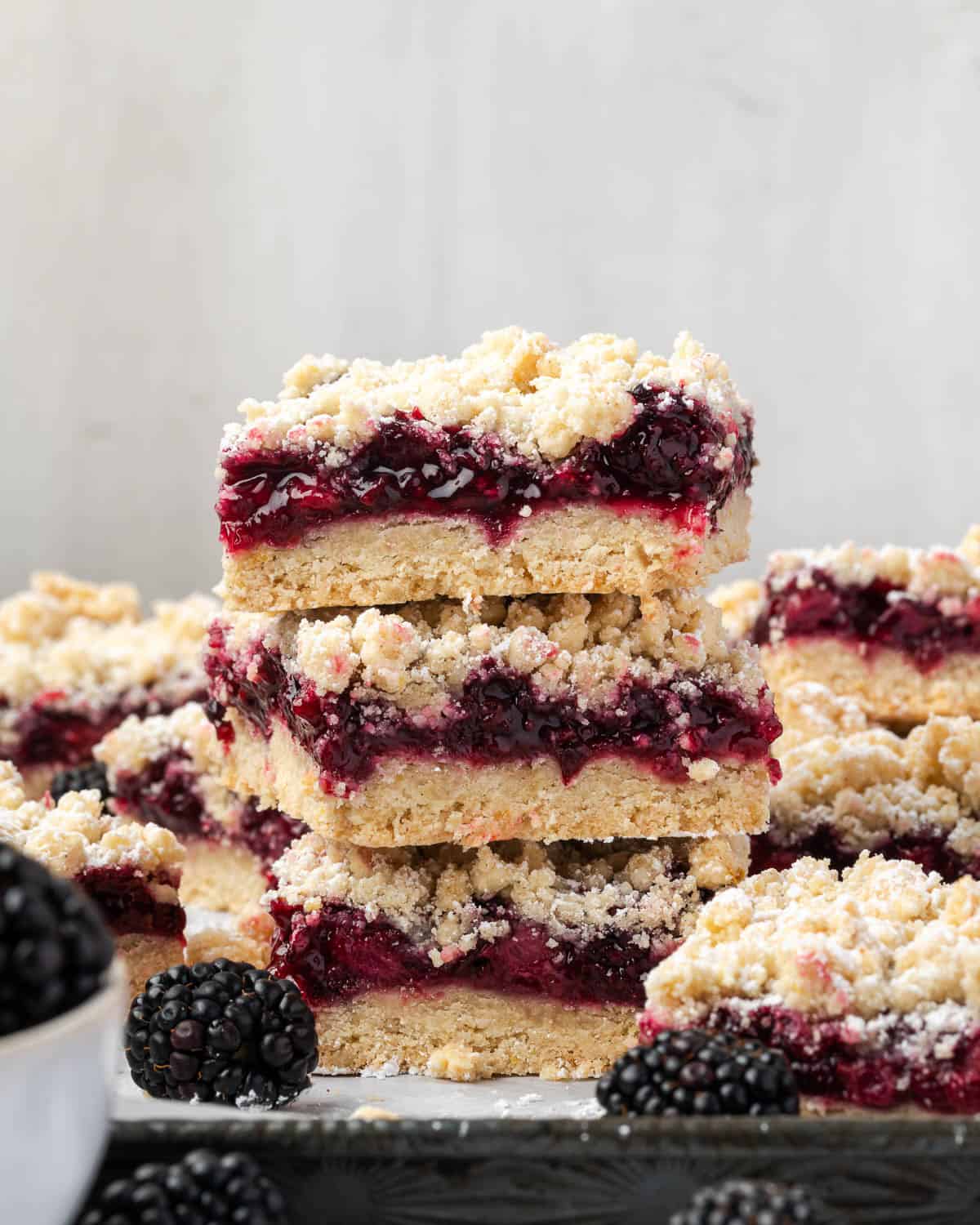 A stack of three blackberry crumb bars sitting on a baking sheet. 