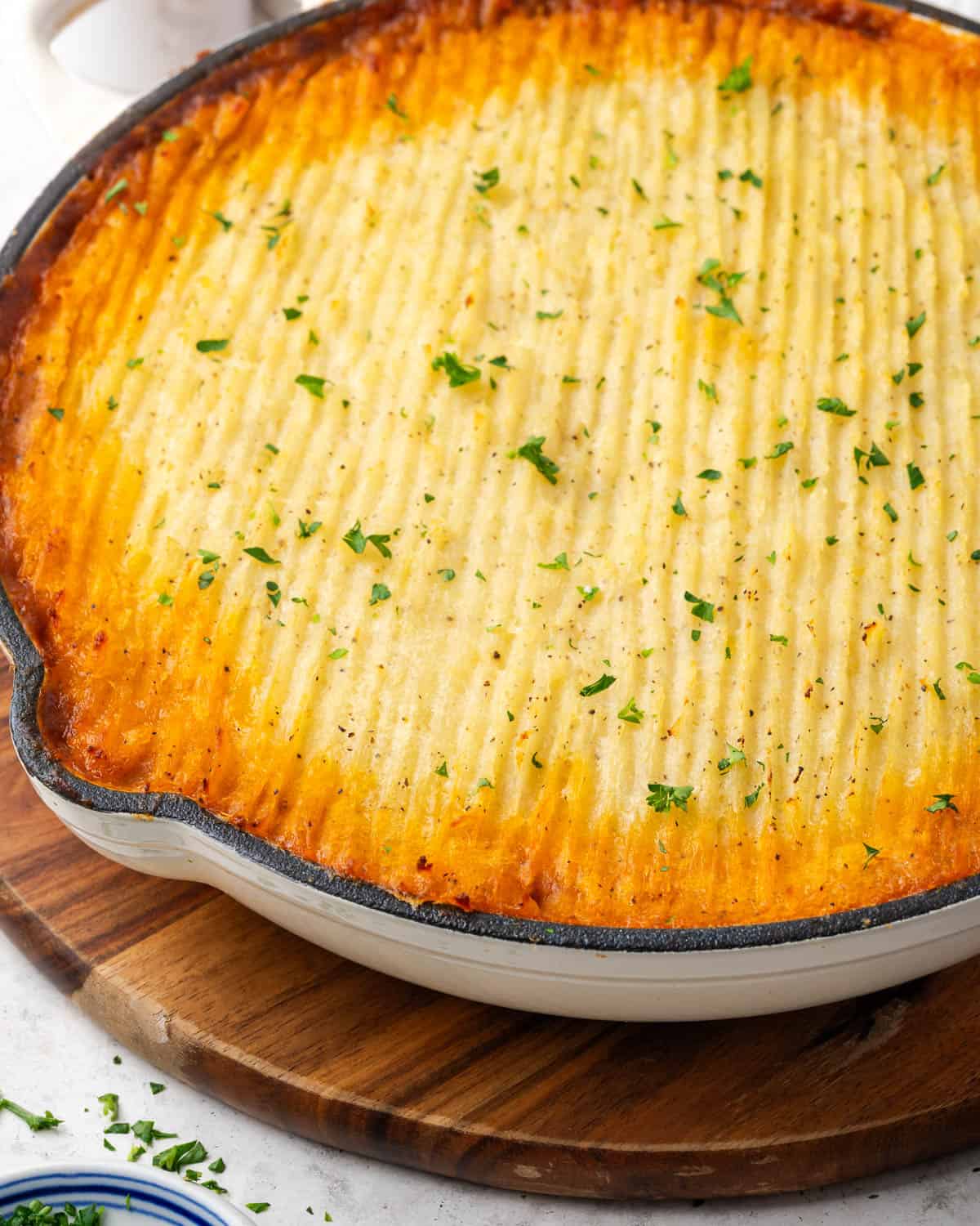A baked cottage pie sitting on a wooden board.