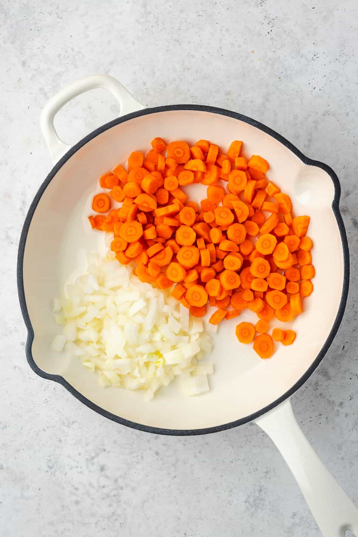 Carrots and onions being sauteed in a skillet. 
