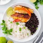 Two fajita stuffed chicken breasts served with white rice and black beans.