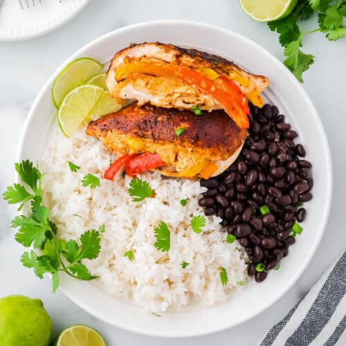 Two fajita stuffed chicken breasts served with white rice and black beans.