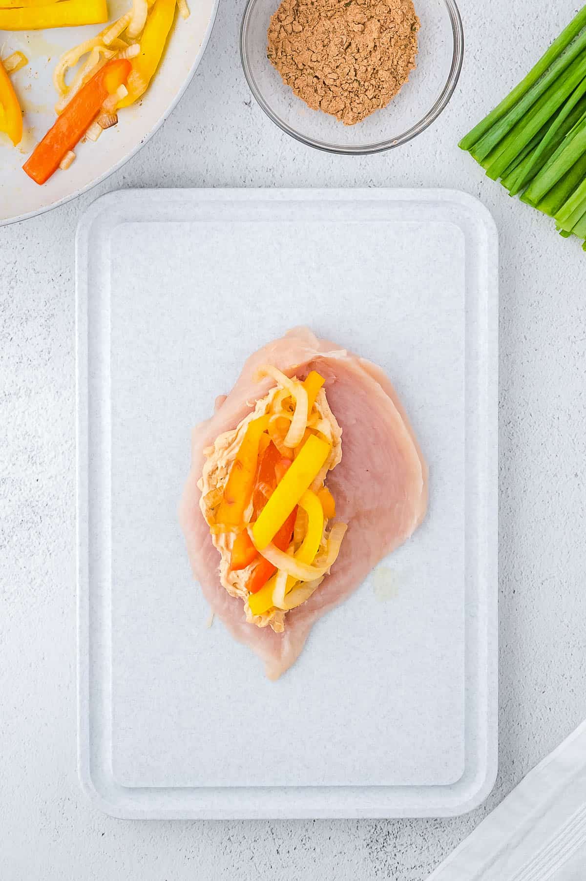 Sliced open chicken breast with the cheese mixture and cooked vegetables on one side. 