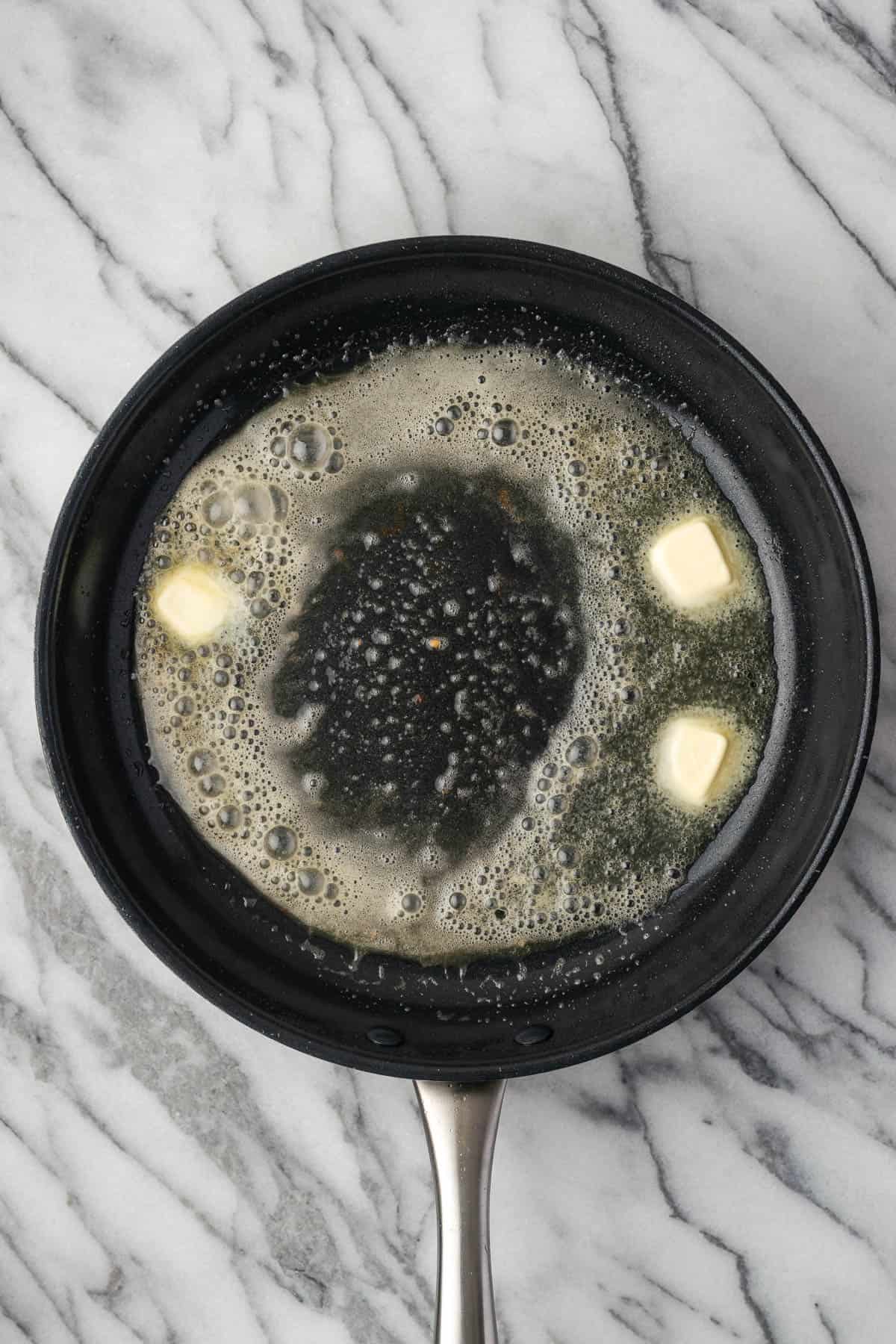Butter melting in a large skillet.