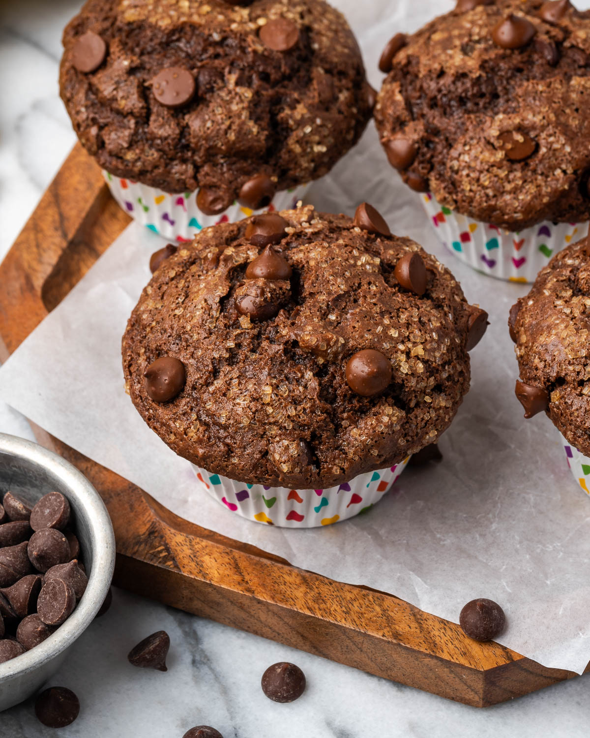Several gluten free chocolate muffins sitting on a wood tray.