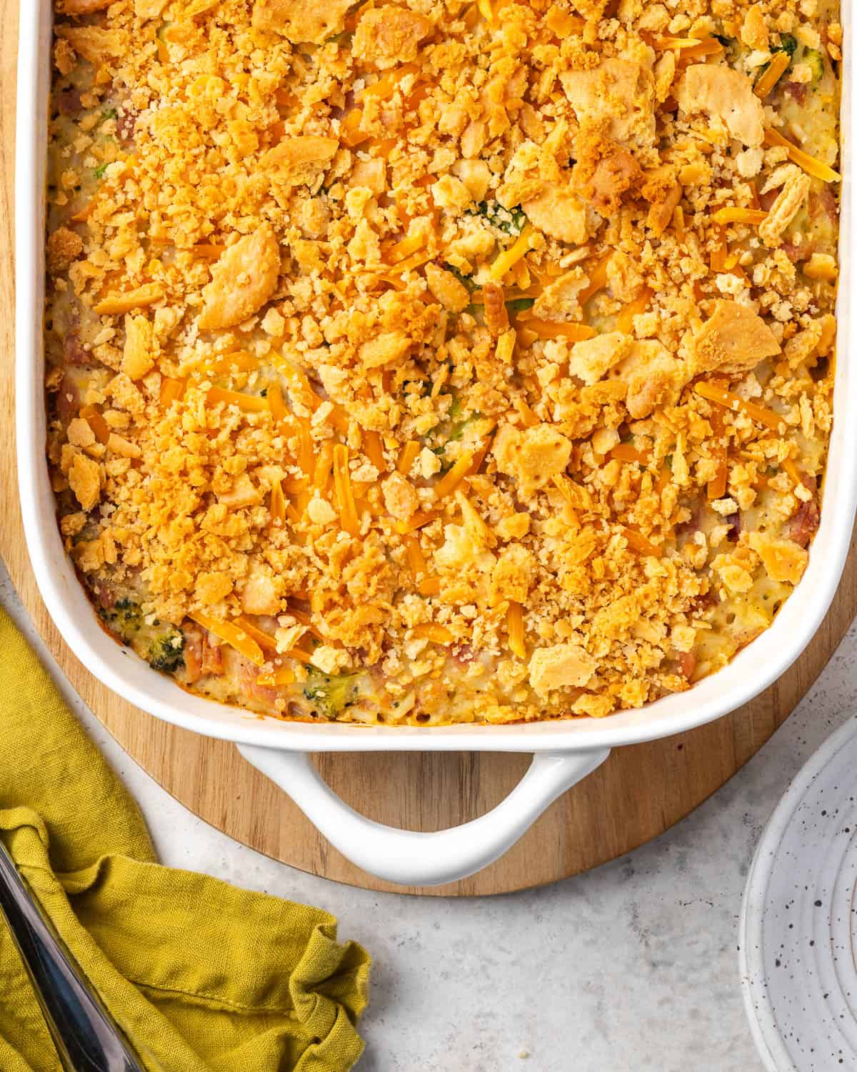 A baked ham and broccoli casserole sitting on a wooden board. 