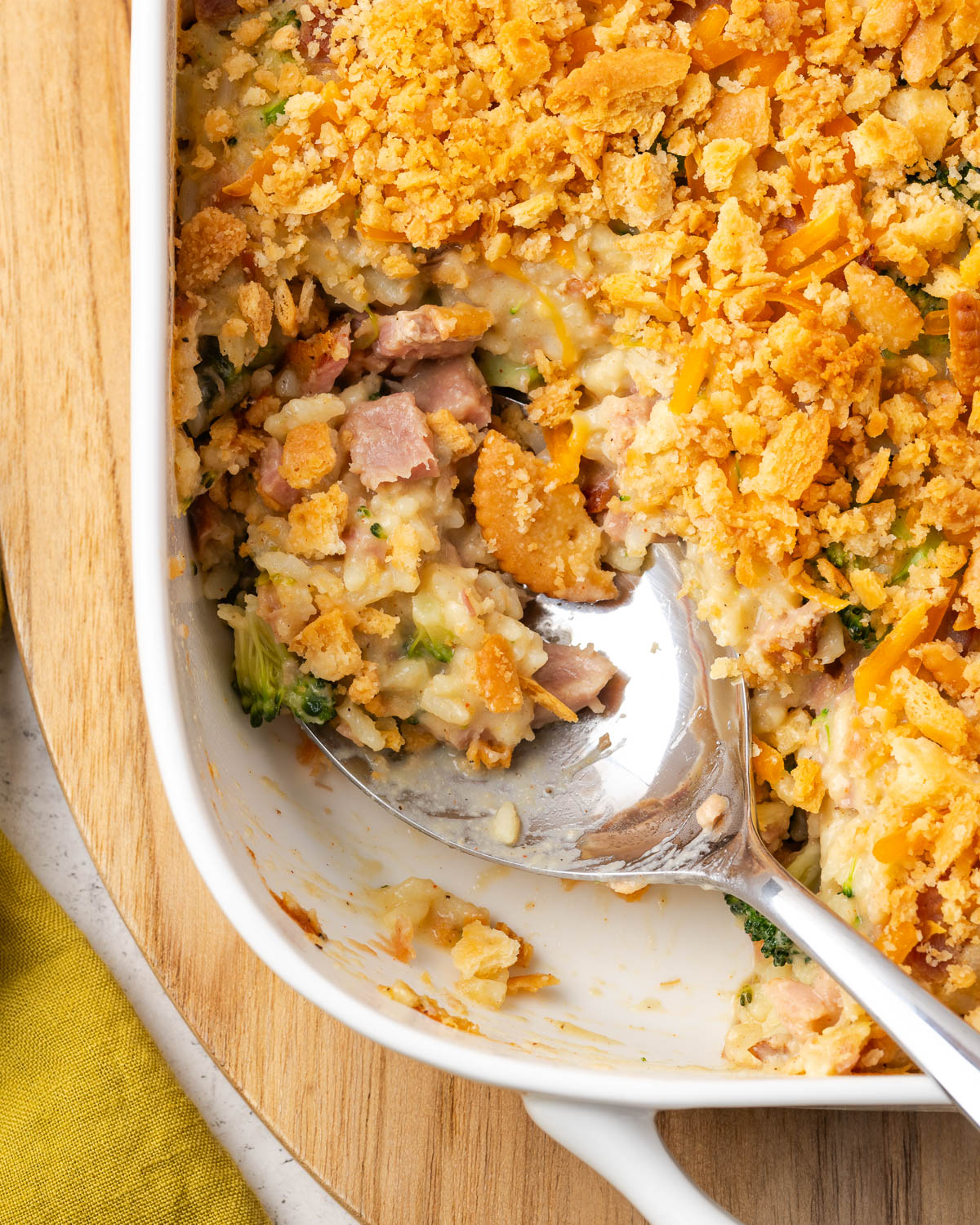 A serving spoon scooping into a ham broccoli and rice casserole.
