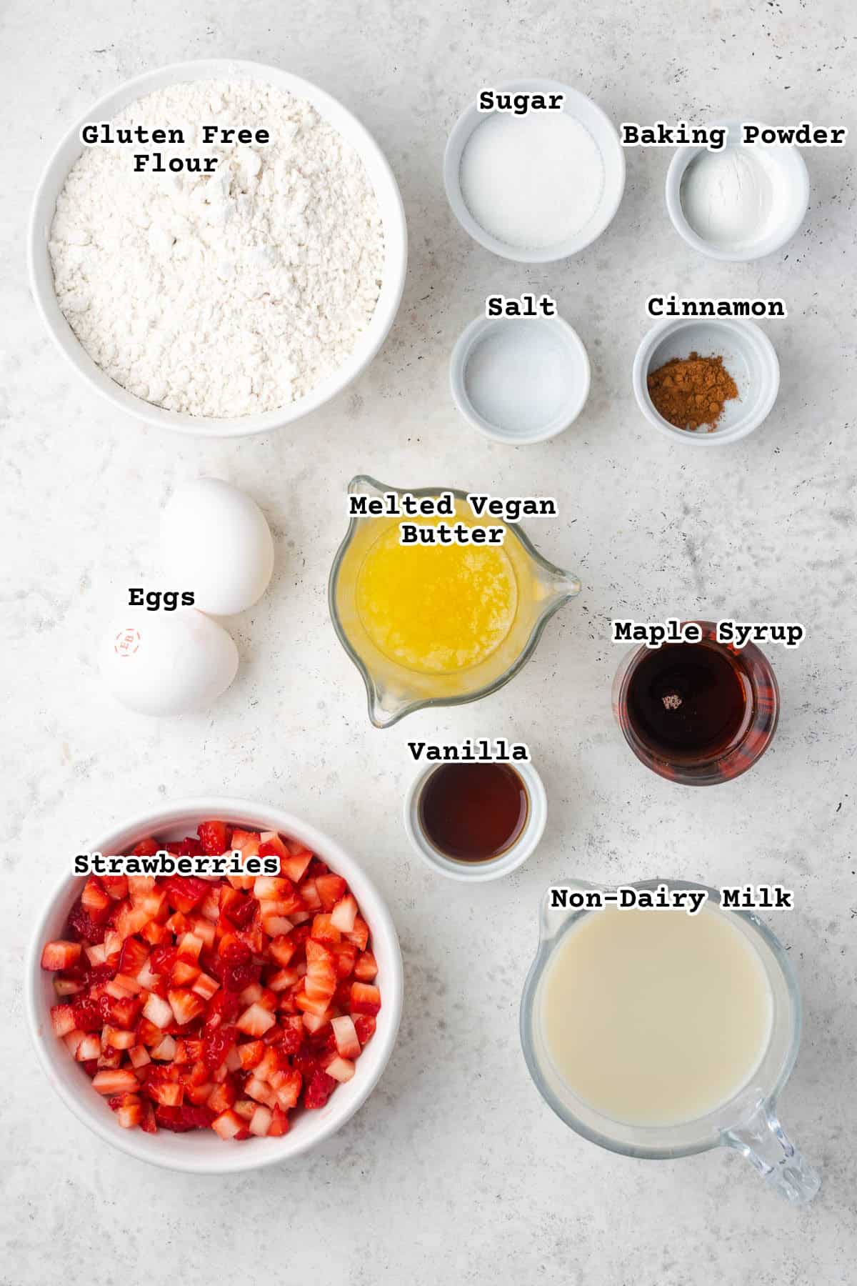 Ingredients for gluten free strawberry waffles on a white counter.